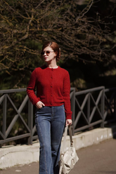 a lady in a red slim sweater and a pair of jeans
